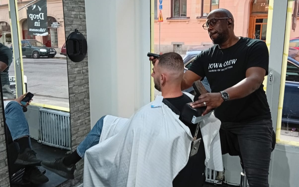 Barberare i Jow & Crew-tröja klipper en kund